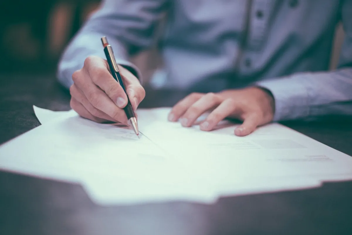 Person processing business documents at a desk — the kind of repetitive manual work that AI agents can automate