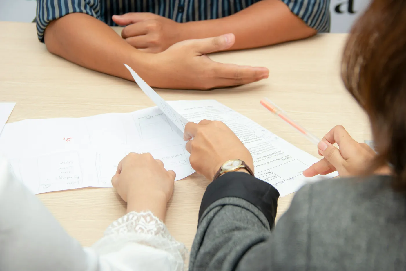 Two people at a meeting table reading through a printed document together, one holding a pen