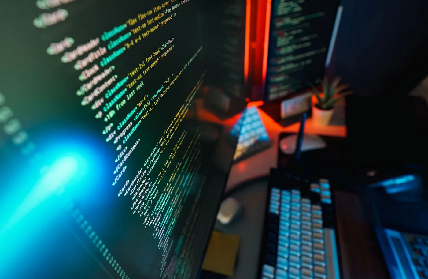 A computer screen filled with colourful source code, lit by ambient neon light in a dark room